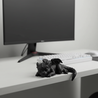 Sleeping baby dragon edge sitter on a modern gaming desk